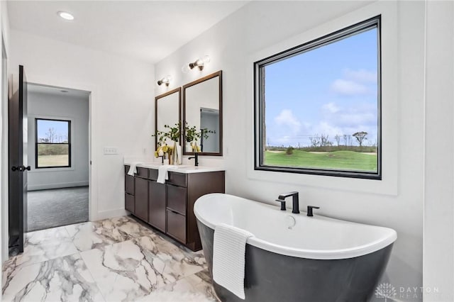 full bathroom featuring a freestanding tub, baseboards, marble finish floor, and vanity