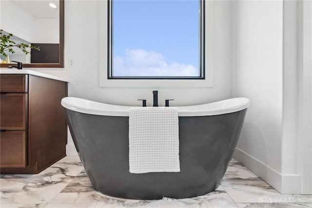 full bathroom featuring vanity, baseboards, a soaking tub, and marble finish floor