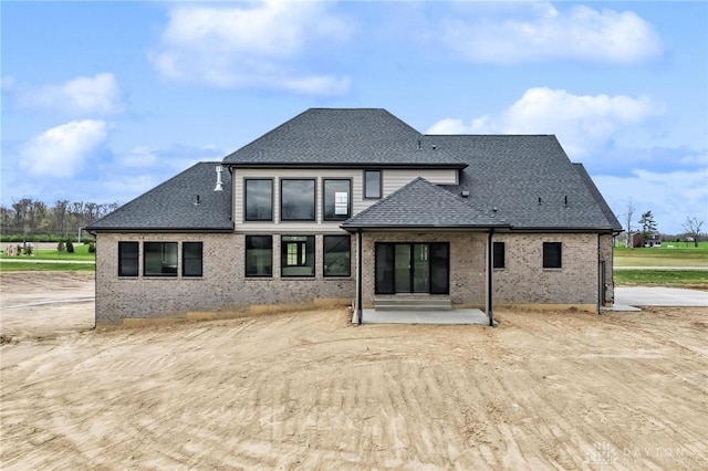 back of property with roof with shingles and brick siding