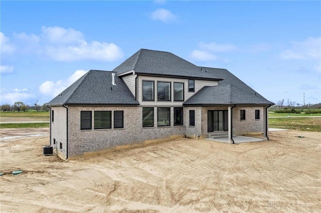 back of house featuring brick siding, roof with shingles, a patio, and cooling unit