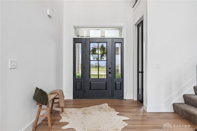 entrance foyer featuring baseboards, wood finished floors, and stairway