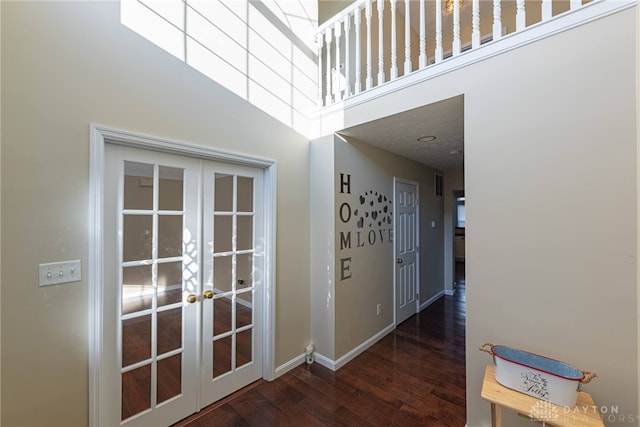 hall featuring dark wood-type flooring, a high ceiling, and french doors