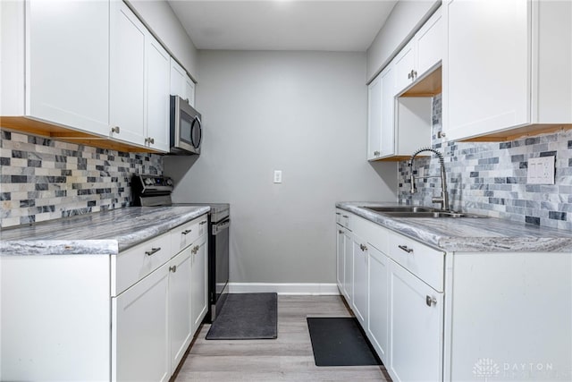 kitchen featuring white cabinetry, sink, light stone counters, and appliances with stainless steel finishes