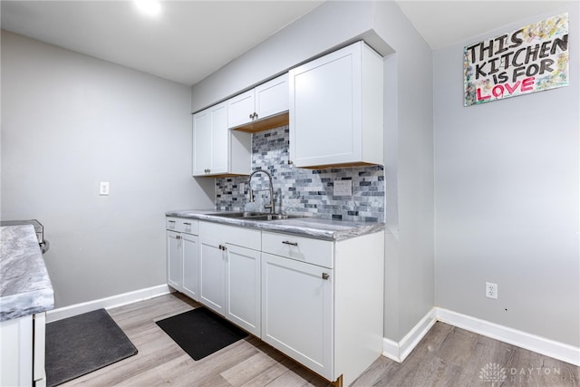 kitchen featuring decorative backsplash, light hardwood / wood-style flooring, white cabinetry, and sink