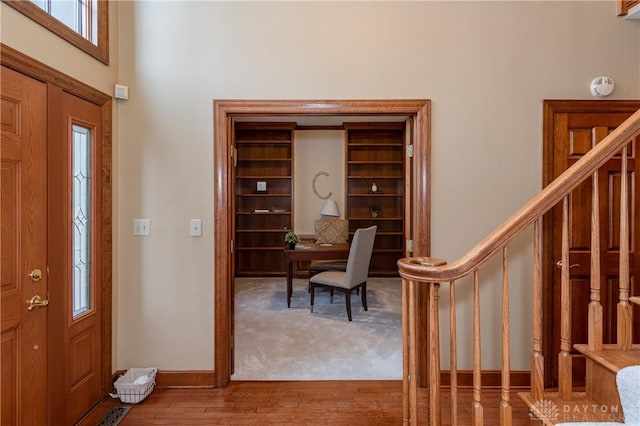 foyer entrance with hardwood / wood-style floors and a towering ceiling