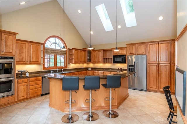 kitchen with a center island, stainless steel appliances, high vaulted ceiling, and a skylight