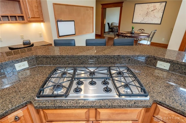 kitchen with stainless steel gas stovetop and dark stone countertops