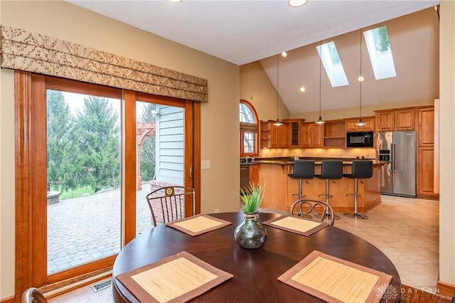 dining area featuring a skylight, high vaulted ceiling, and a healthy amount of sunlight