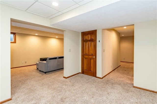 interior space with a paneled ceiling and light carpet