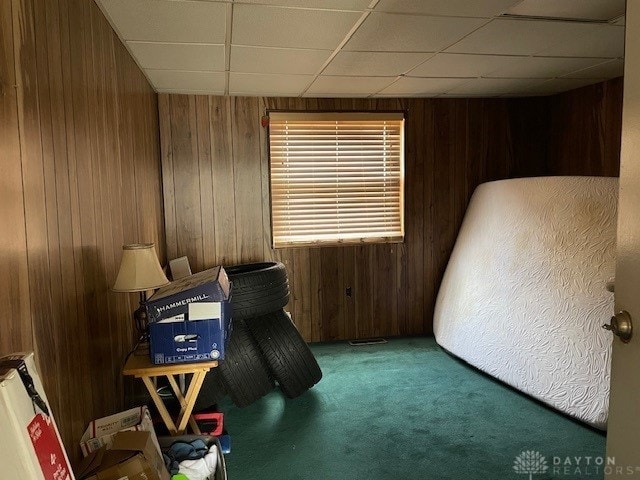 miscellaneous room featuring carpet, a paneled ceiling, and wood walls