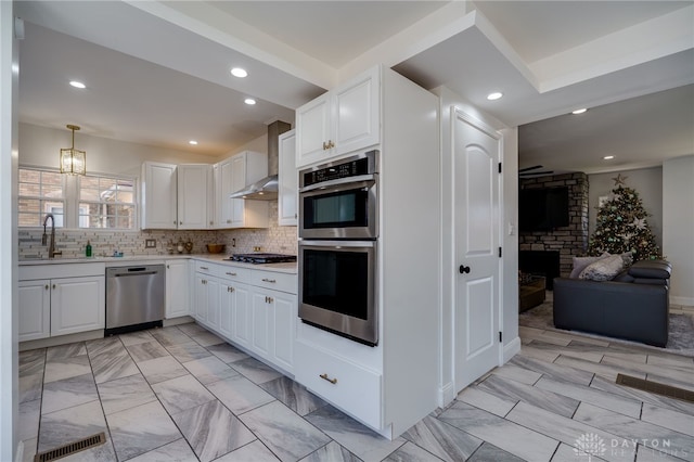 kitchen with hanging light fixtures, sink, white cabinets, and stainless steel appliances