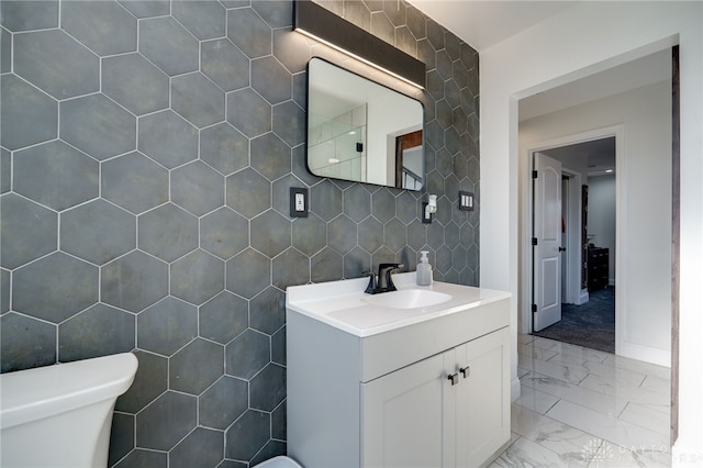 bathroom with vanity, tile walls, and toilet