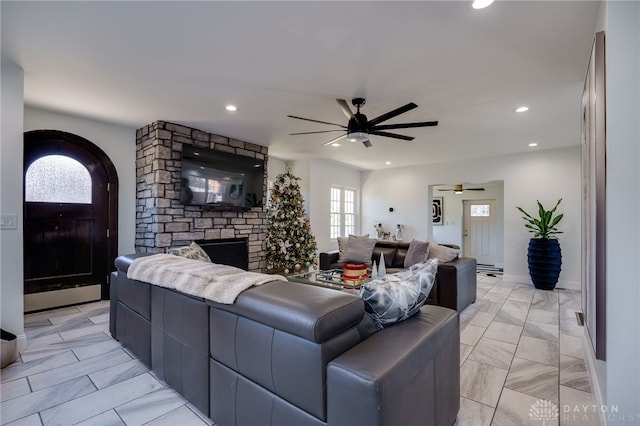 living room featuring a stone fireplace and ceiling fan