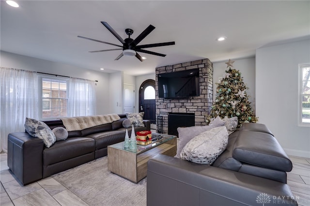 living room featuring a fireplace, ceiling fan, and a healthy amount of sunlight