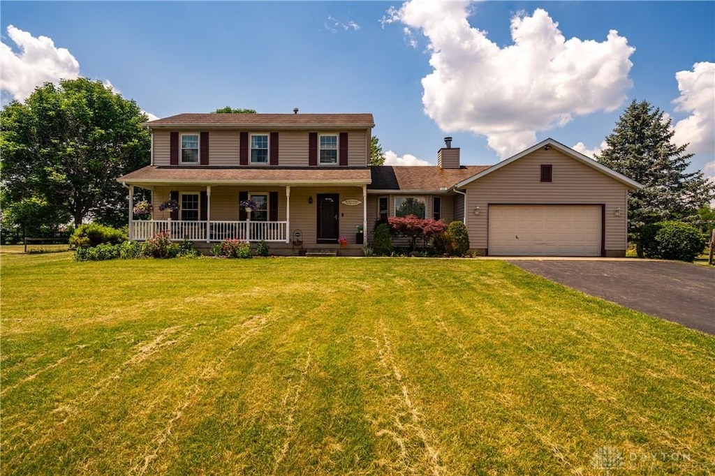 view of front of property featuring covered porch, a front yard, and a garage