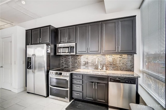 kitchen featuring sink, decorative backsplash, light tile patterned floors, appliances with stainless steel finishes, and light stone counters