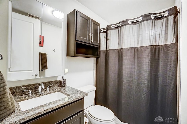 bathroom featuring vanity, toilet, and walk in shower