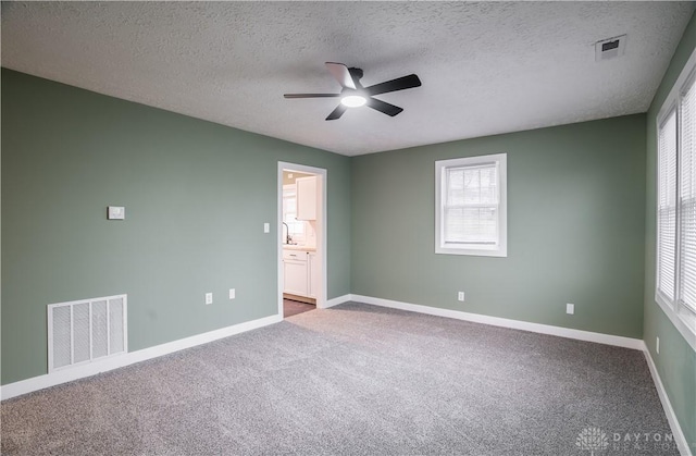 unfurnished bedroom with ceiling fan, connected bathroom, carpet flooring, and a textured ceiling