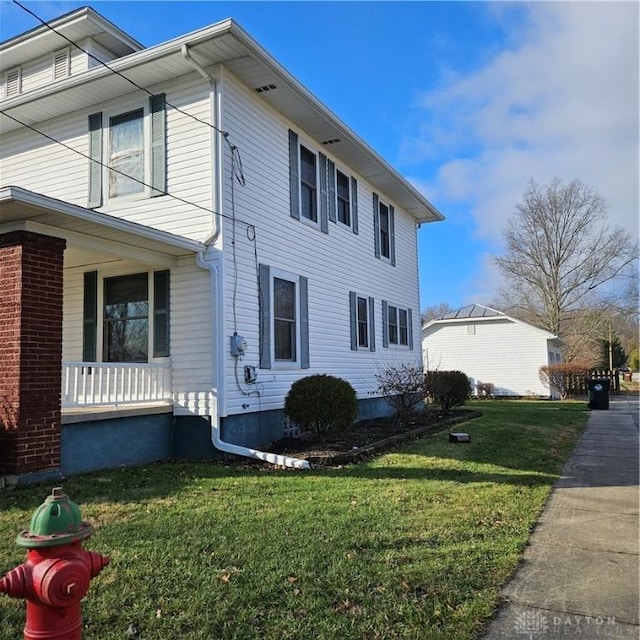 view of side of home featuring a yard and a porch