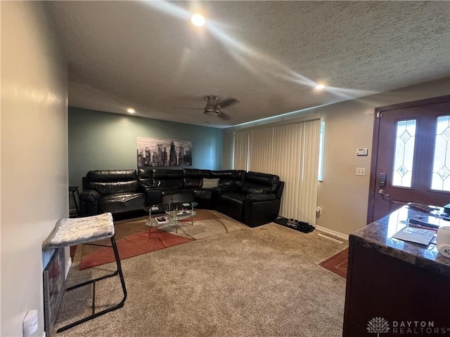 living room featuring ceiling fan, carpet floors, and a textured ceiling