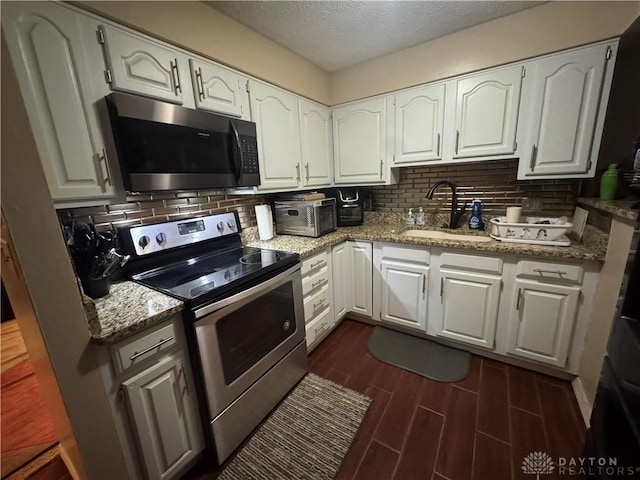 kitchen featuring light stone counters, sink, white cabinets, and stainless steel appliances