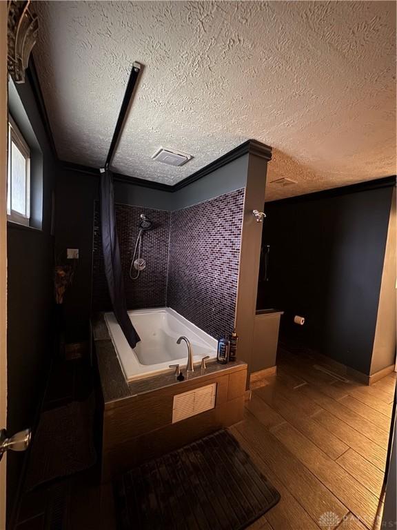 bathroom with hardwood / wood-style floors, plus walk in shower, and a textured ceiling