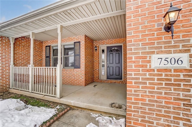 snow covered property entrance with covered porch