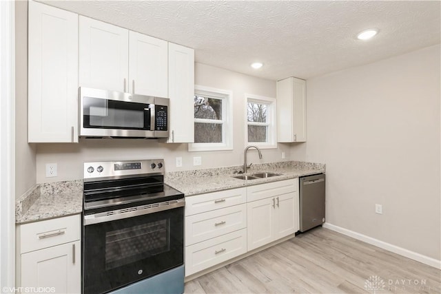 kitchen with white cabinets, stainless steel appliances, light hardwood / wood-style flooring, and sink