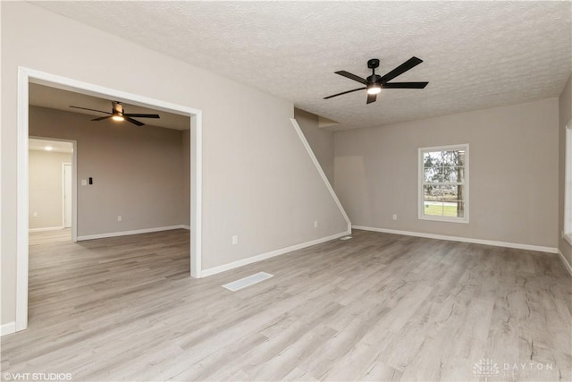 spare room with a textured ceiling, light wood-type flooring, and ceiling fan