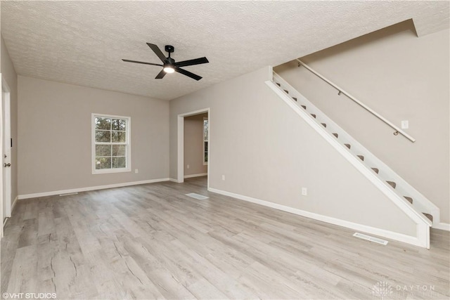 unfurnished living room with a textured ceiling, light hardwood / wood-style floors, and ceiling fan