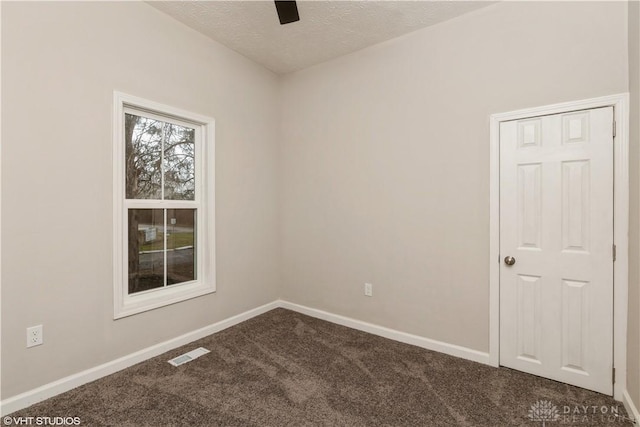 spare room with dark carpet and a textured ceiling