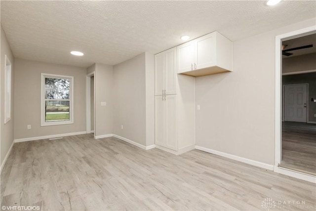 spare room featuring a textured ceiling and light wood-type flooring