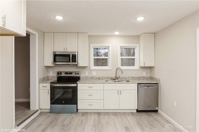 kitchen featuring light stone counters, sink, white cabinets, and appliances with stainless steel finishes