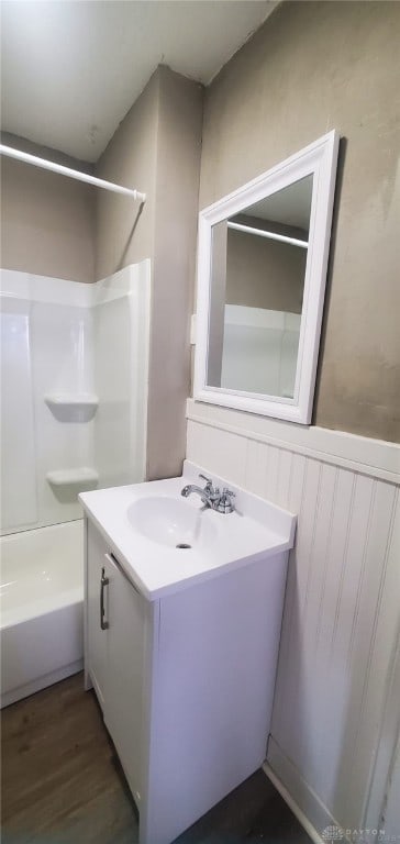 bathroom with hardwood / wood-style floors, vanity, and bathing tub / shower combination