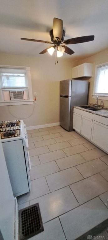 kitchen featuring stainless steel fridge, white gas range oven, white cabinetry, and sink