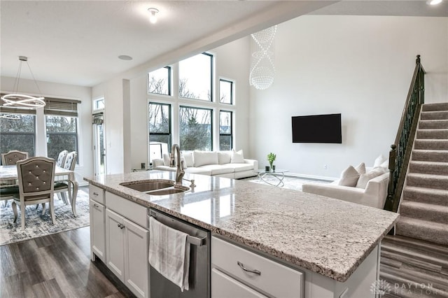 kitchen with sink, hanging light fixtures, stainless steel dishwasher, a center island with sink, and white cabinets