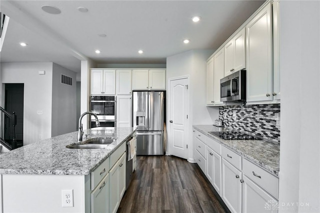 kitchen with sink, dark wood-type flooring, stainless steel appliances, a center island with sink, and white cabinets