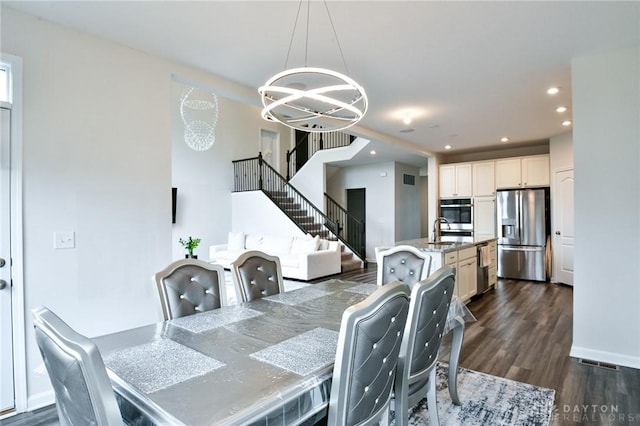 dining room with dark hardwood / wood-style flooring, a notable chandelier, and sink