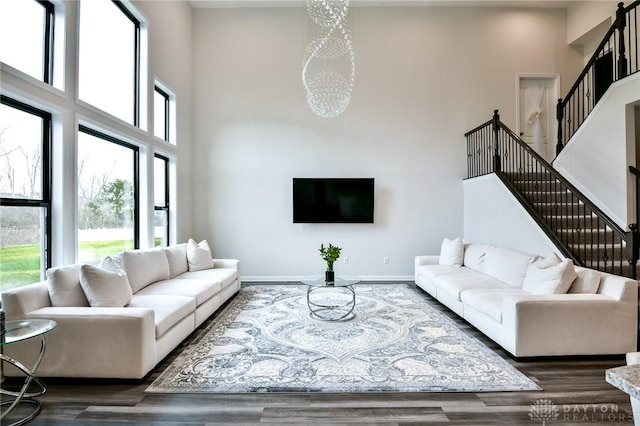 living room with a notable chandelier, dark hardwood / wood-style flooring, and a towering ceiling