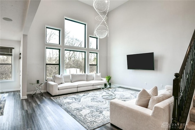 living room featuring a notable chandelier, a towering ceiling, and dark wood-type flooring