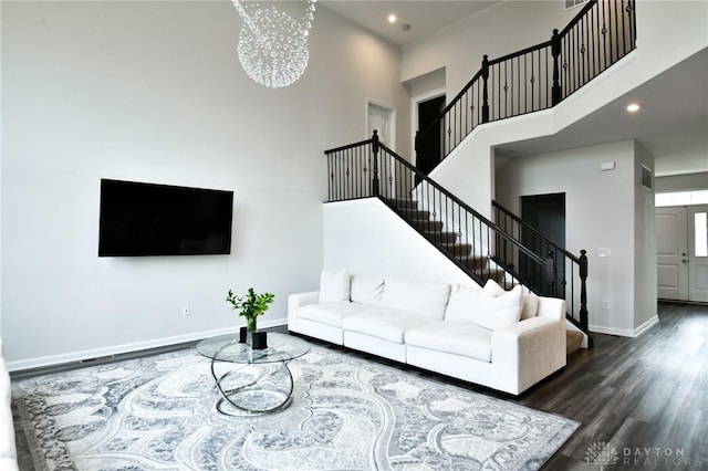 living room with dark hardwood / wood-style flooring, a towering ceiling, and a chandelier