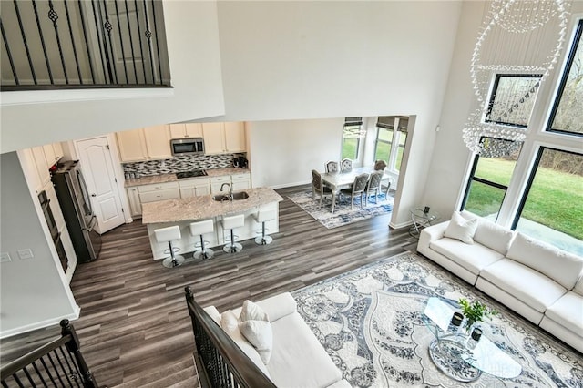 living room featuring sink, dark hardwood / wood-style flooring, a towering ceiling, and an inviting chandelier