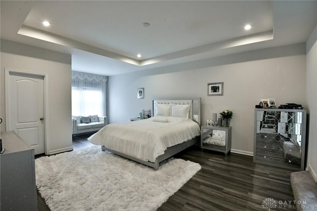 bedroom with a tray ceiling and dark wood-type flooring