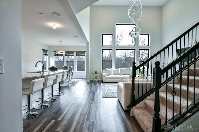 living room with sink, a high ceiling, dark hardwood / wood-style floors, and an inviting chandelier