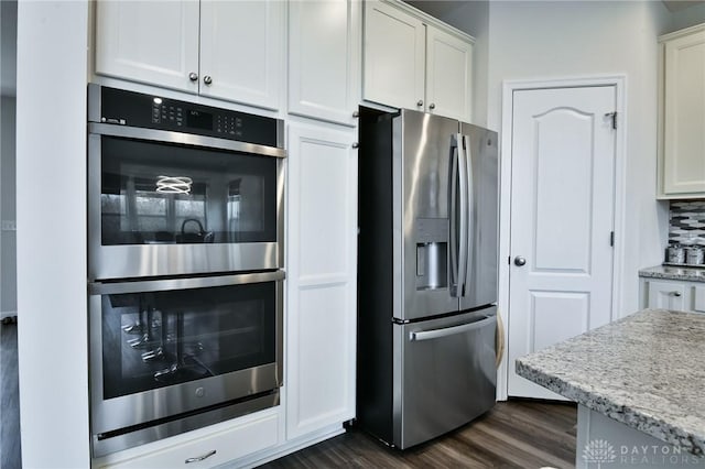 kitchen featuring dark hardwood / wood-style flooring, tasteful backsplash, light stone counters, stainless steel appliances, and white cabinetry