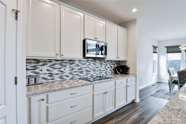 kitchen featuring white cabinets, decorative backsplash, dark hardwood / wood-style floors, black electric cooktop, and light stone counters