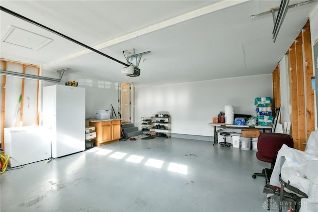 garage featuring white refrigerator, refrigerator, and a garage door opener