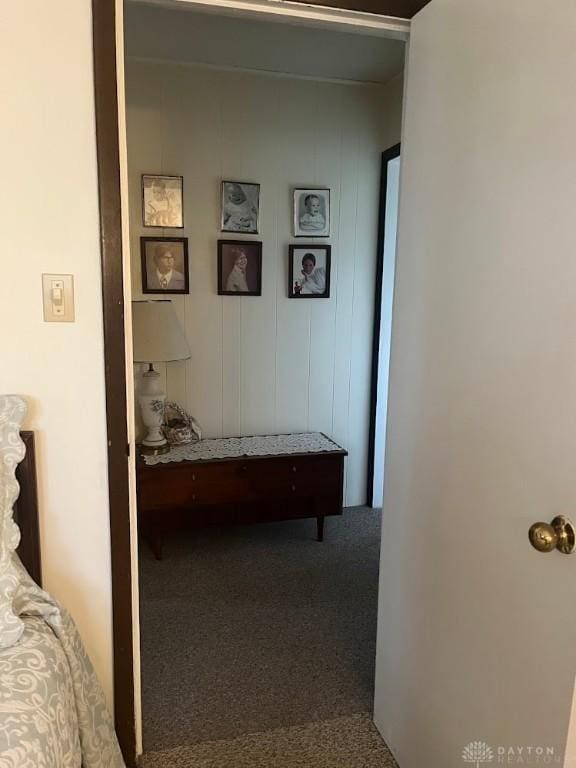 hallway with carpet flooring and wooden walls