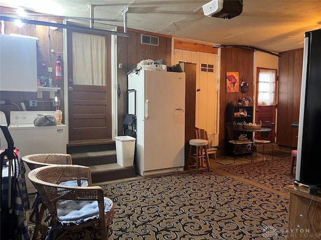 interior space featuring washer / dryer, white refrigerator, a garage door opener, and wood walls