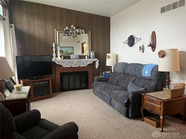 living room featuring carpet, wood walls, and a fireplace